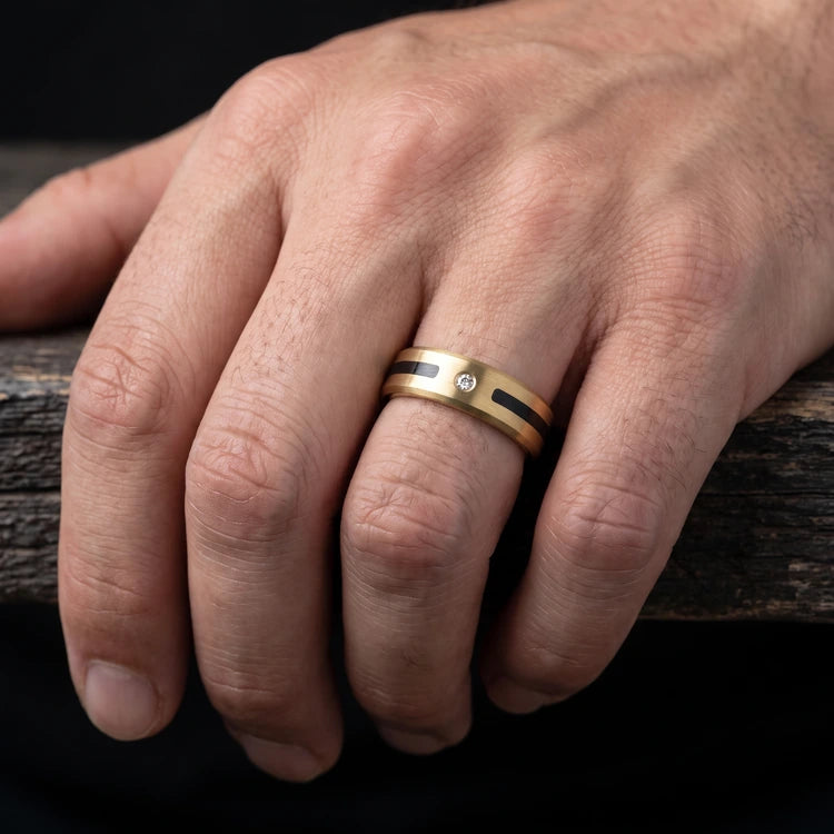 Hand wearing a 6mm 10K yellow gold men’s beveled wedding band with a unidirectional central inlay and brushed finish