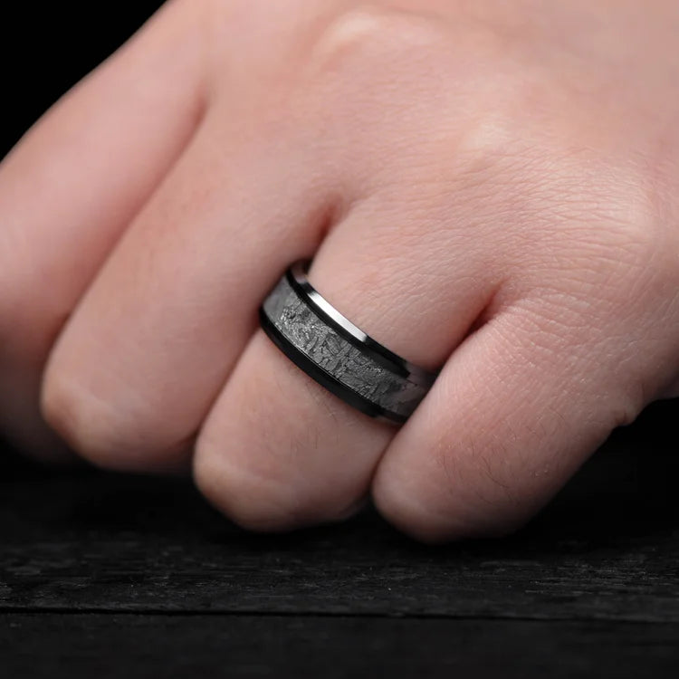 Black titanium ring featuring a central meteorite inlay and bloodwood inner sleeve, 8mm mens wedding band with free engraving, unique design on white background.