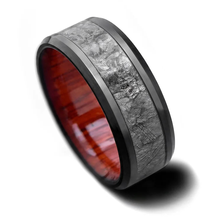 Black titanium ring featuring a central meteorite inlay and bloodwood inner sleeve, 8mm mens wedding band with free engraving, unique design on white background.