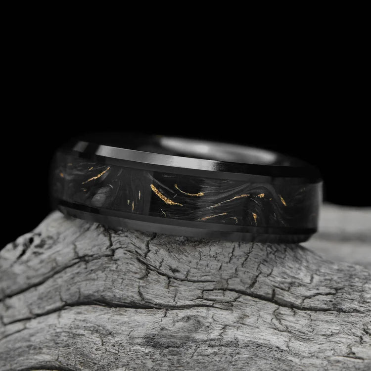 Black titanium mens wedding band with gilded forged inlay, 7mm width, polished bevel profile, unique design, free engraving, displayed on a white sea branch.