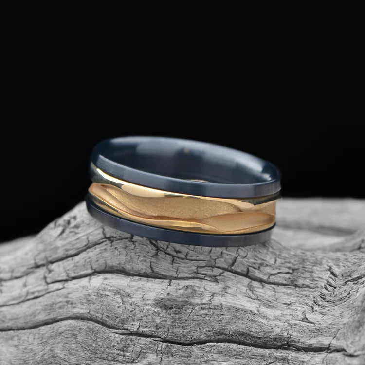 ALT text: "Black Titanium Ring with 18KY Wave Central Inlay, Men's Wedding Band, 8mm Polished Domed Profile, Custom Men's Ring on White Sea Branch"