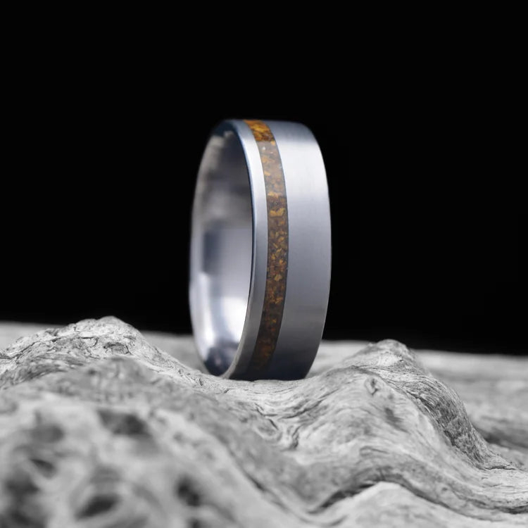 Tantalum wedding band with tiger's eye inlay, 7mm brushed flat profile, men's custom ring on white sea branch.