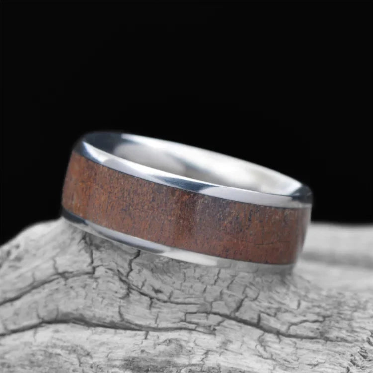 Titanium men's wedding band with central dinobone inlay, 7mm, unique custom design, free engraving, displayed on a white sea branch.