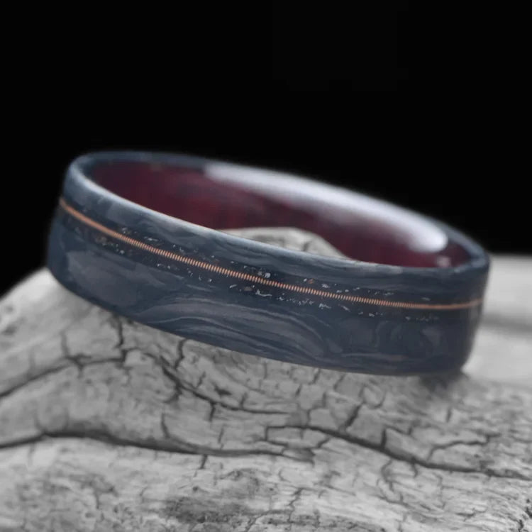 Men's 6mm matte flat profile forged wedding band with meteorite and guitar string inlay, featuring a bloodwood inner sleeve, free engraving available, displayed on a white sea branch.