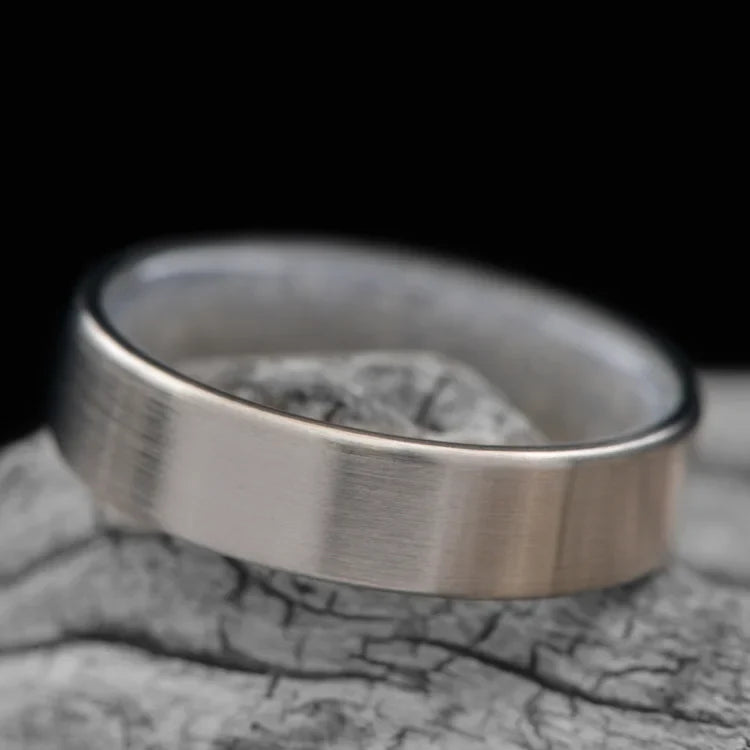 14KW mens wedding band with moonstone inner sleeve, brushed flat profile, 6mm width, custom design, free engraving, displayed on a white sea branch.