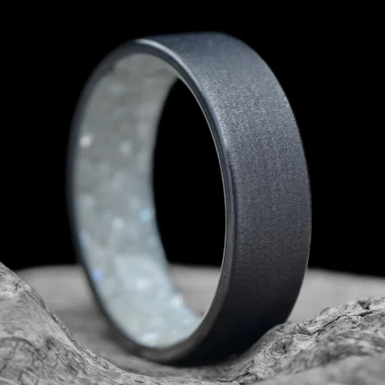 Black Titanium Wedding Band with Granite Finish and Pearl Inner Sleeve, 7mm Mens Custom Ring, displayed on white sea branch, offering free engraving.