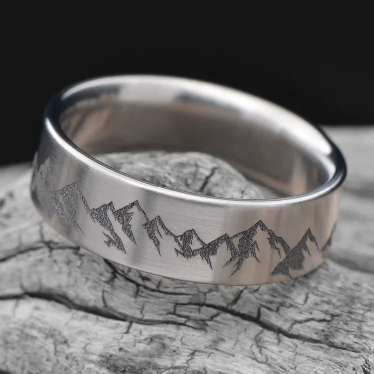 Titanium wedding band with brushed finish, 7mm mens ring, custom engraving available, displayed on a white sea branch.