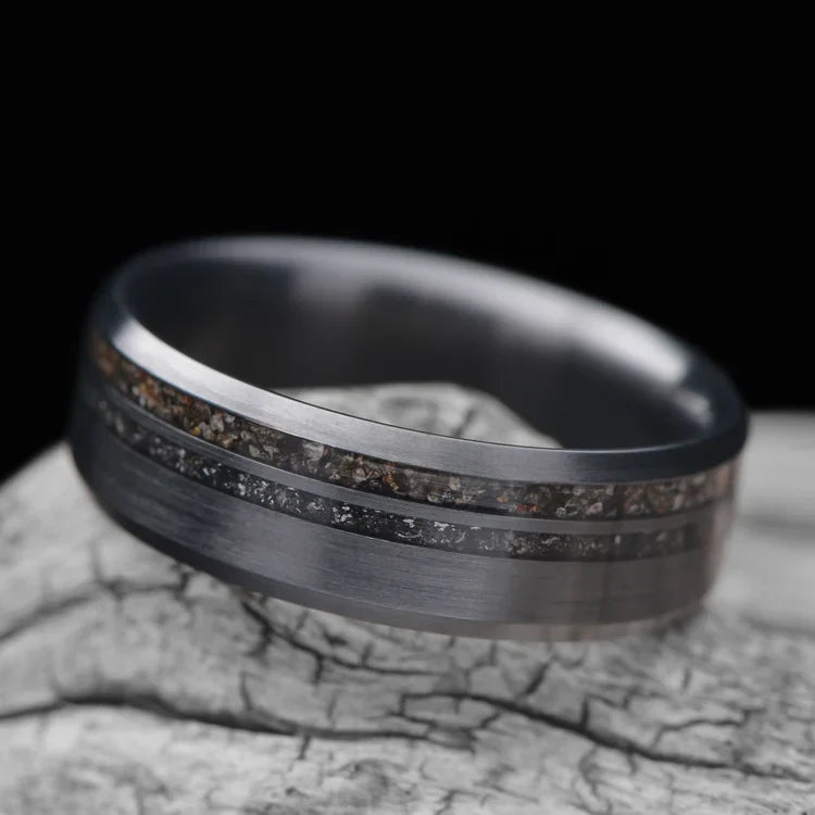 Zirconium wedding band with crushed T-Rex and meteorite inlays, 7mm mens ring, unique brushed bevel profile, free engraving, displayed on a white sea branch.