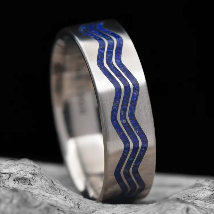 Titanium wedding band with lapis lazuli inlay, 7mm mens ring, unique custom design, free engraving, displayed on white sea branch.
