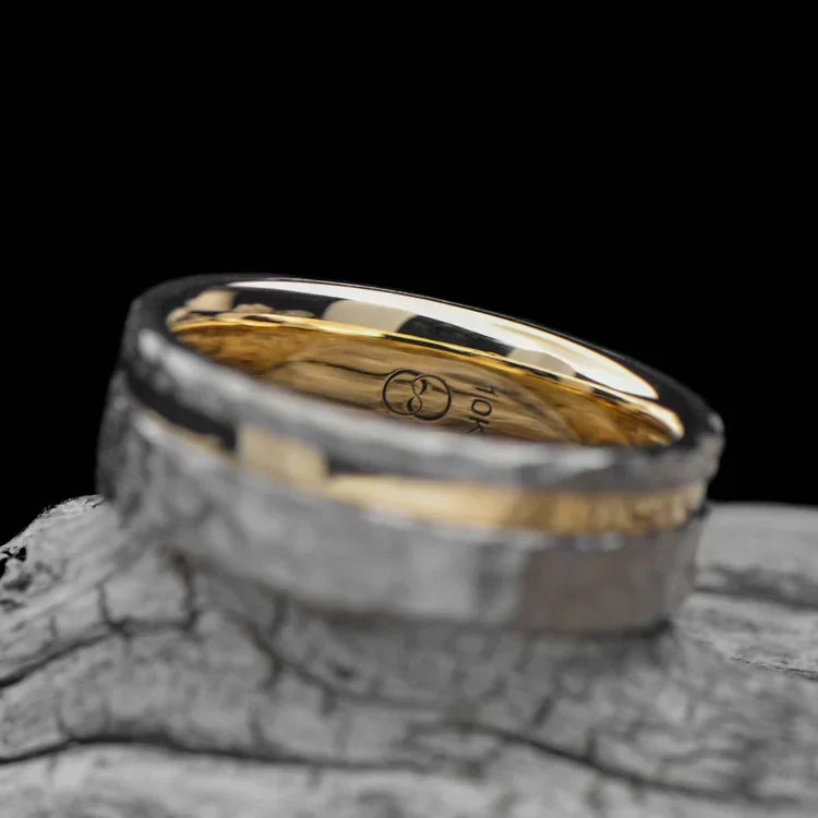 Titanium wedding band with 10KY inlay, featuring a faceted flat profile, 7mm wide, mens unique custom design, free engraving, displayed on a white sea branch.