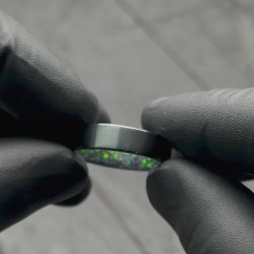 Black Titanium Wedding Band with Black Emerald Opal Inner Sleeve, 6mm Mens Wedding Ring, Polished Flat Profile, Free Engraving, showcased with black gloves.