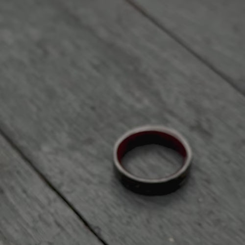 Men's 6mm matte flat profile forged wedding band with meteorite and guitar string inlay, featuring a bloodwood inner sleeve, showcased with black gloves, free engraving available.